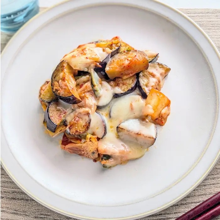 プレートの上に盛り付けられた、チーズがとろけた野菜と肉の料理。