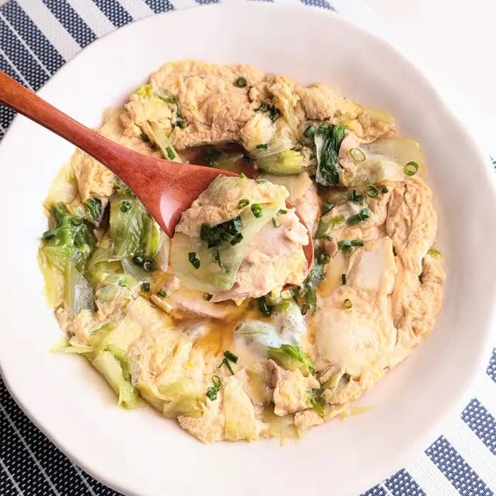 木製スプーンで取り分けられた白菜と卵の料理が皿に盛られている。