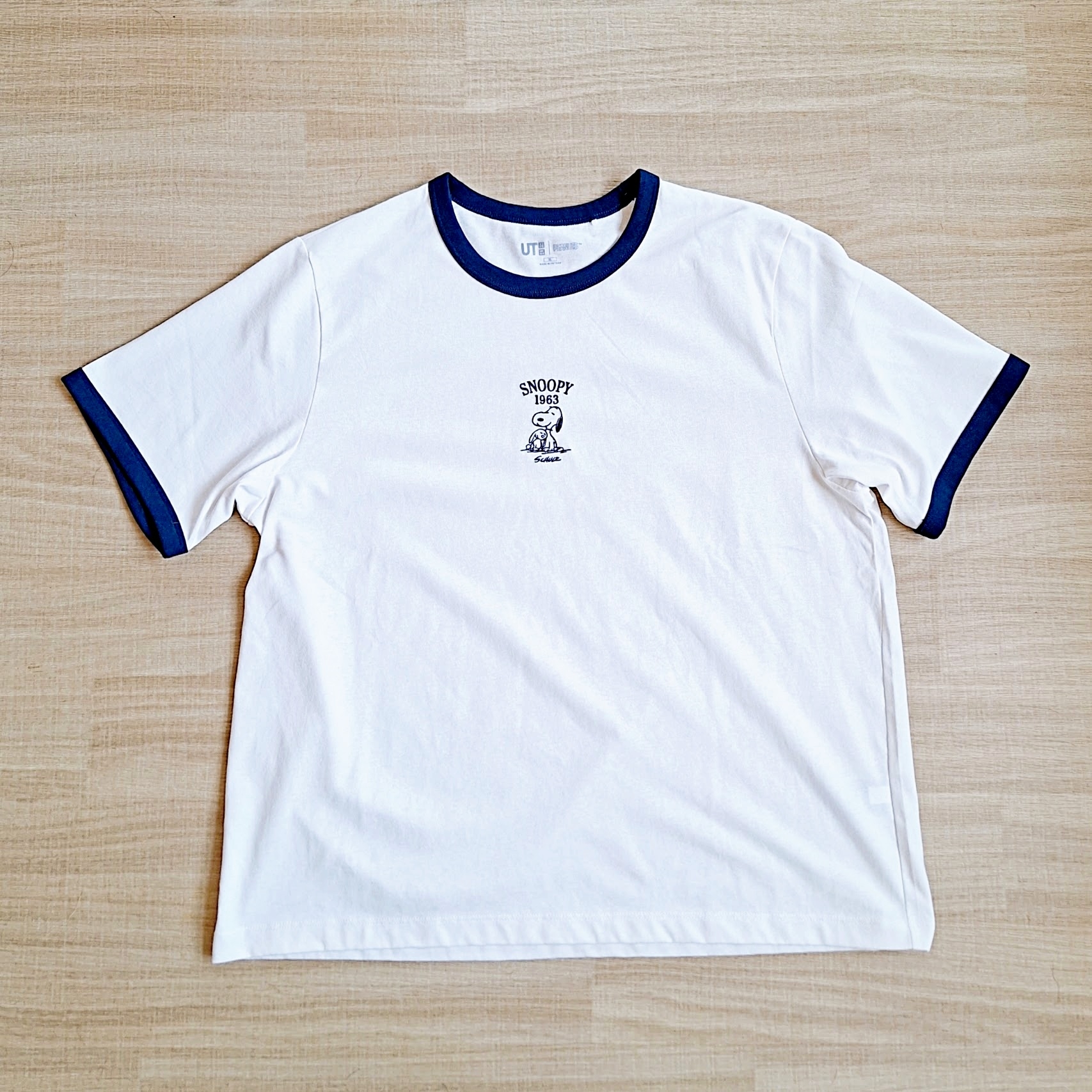 スヌーピーと「PEANUTS」の文字が付いた白いTシャツが床に置かれている。