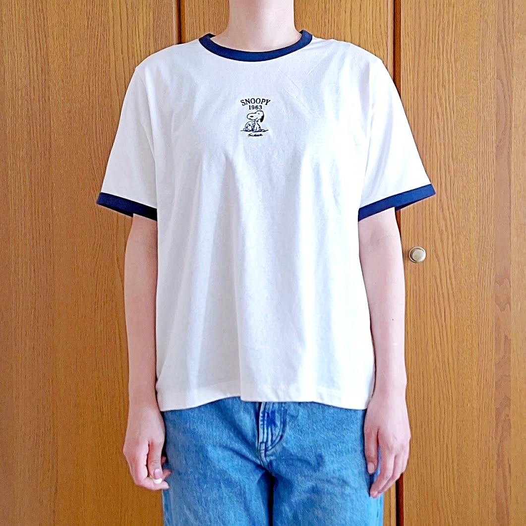 女性がスヌーピーのTシャツとジーンズを着て立っている。