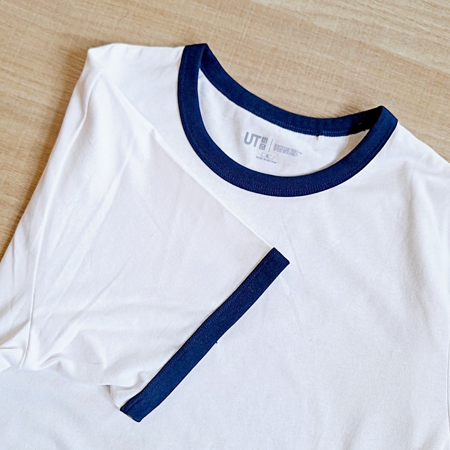 白いTシャツがテーブルに置かれている。ユニクロのUTロゴがタグに見える。