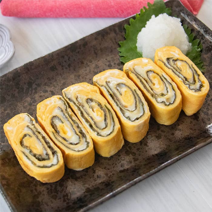 のりとスライスチーズが入った卵焼きが皿に6切れ並べられており、大根おろしが添えられている。