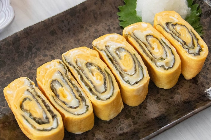 のりとスライスチーズが入った卵焼きが皿に6切れ並べられており、大根おろしが添えられている。