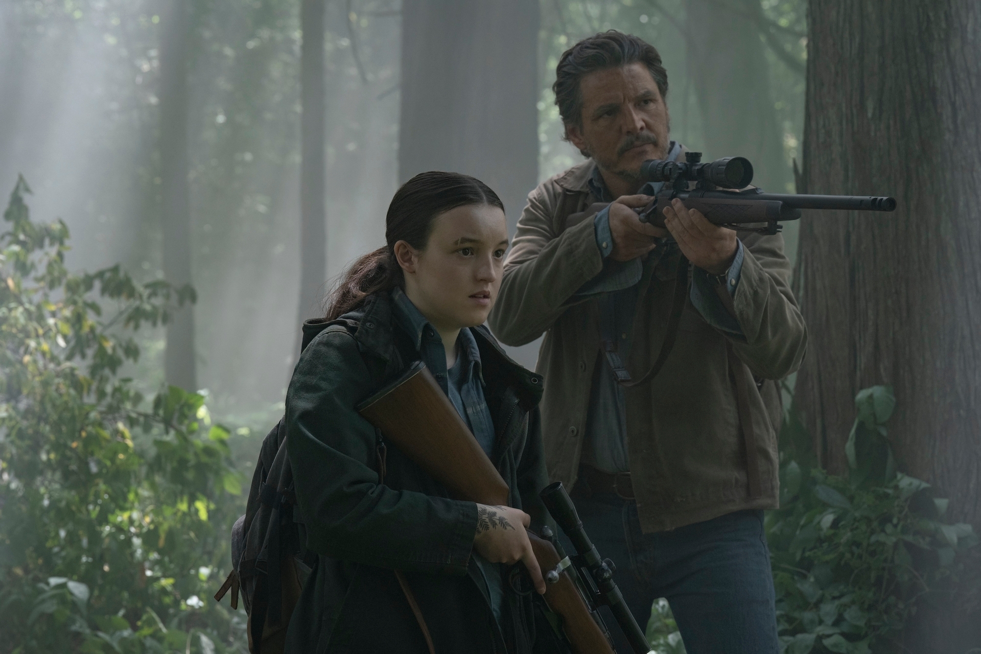 Ellie and Joel in the woods, with Joel pointing a gun