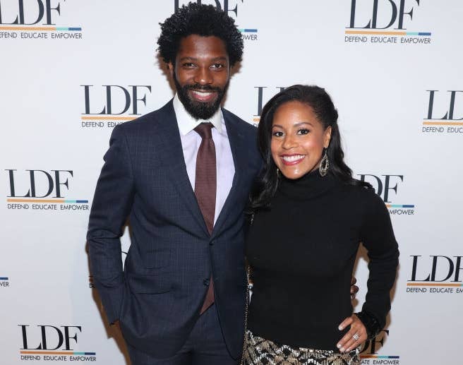 Two people at an event. The man is in a suit and tie, and the woman is in a patterned skirt and black top. LDF logo on the backdrop