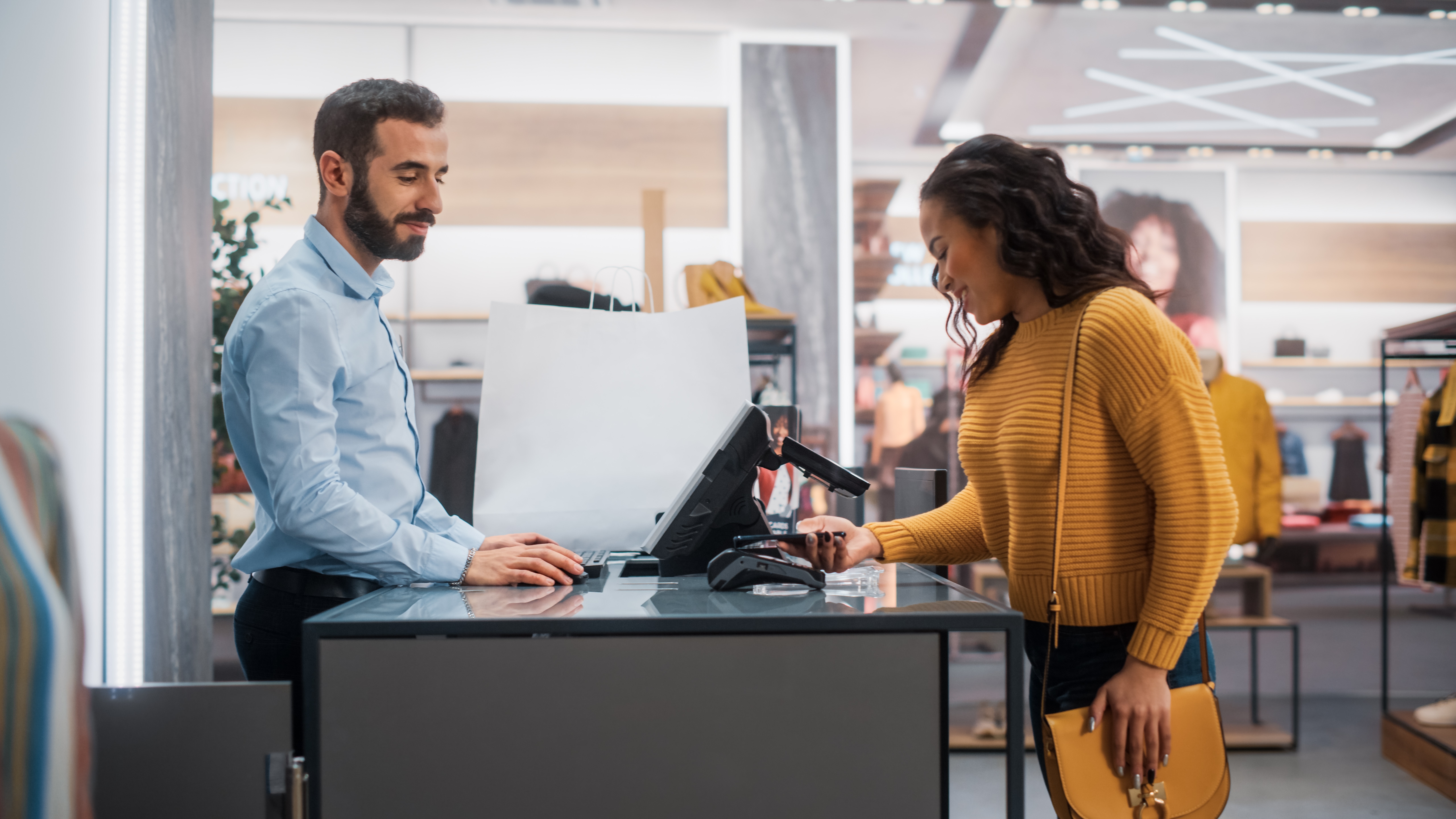 A person purchases an item at a retail store counter, interacting with a cashier