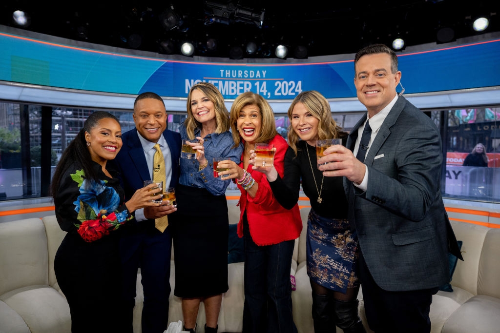 Group of six people on a studio set holding drinks, smiling at the camera. The date "Thursday, November 14, 2024" is displayed above them