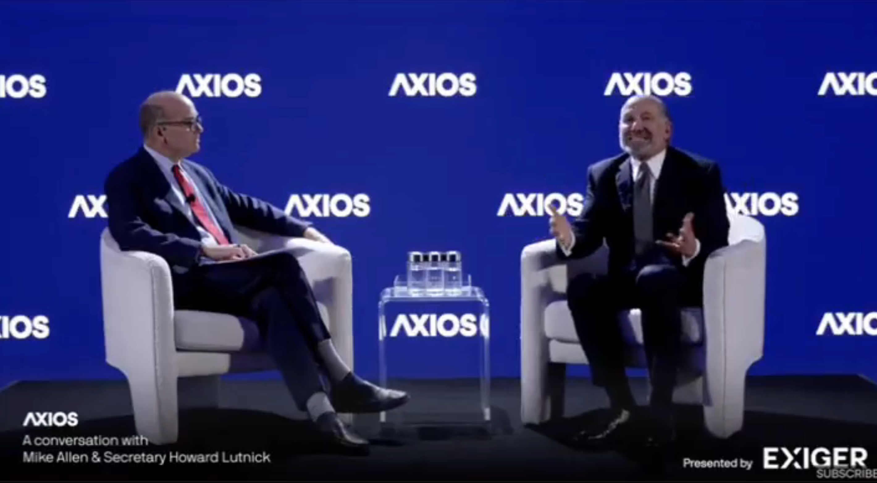 Two people seated on stage during an Axios conversation event, engaged in discussion