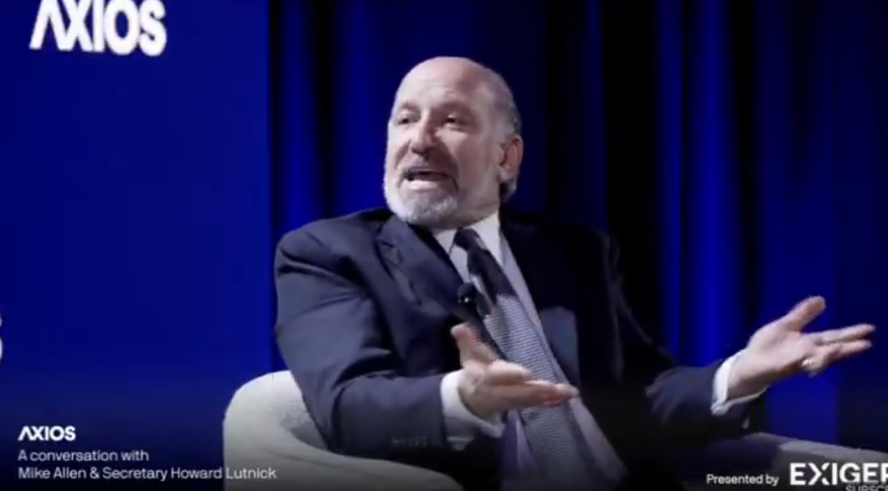 A man speaks energetically while seated on stage with &quot;Axios&quot; branding visible; text reads: &quot;A conversation with Mike Allen &amp;amp; Secretary Howard Lutnick.&quot;