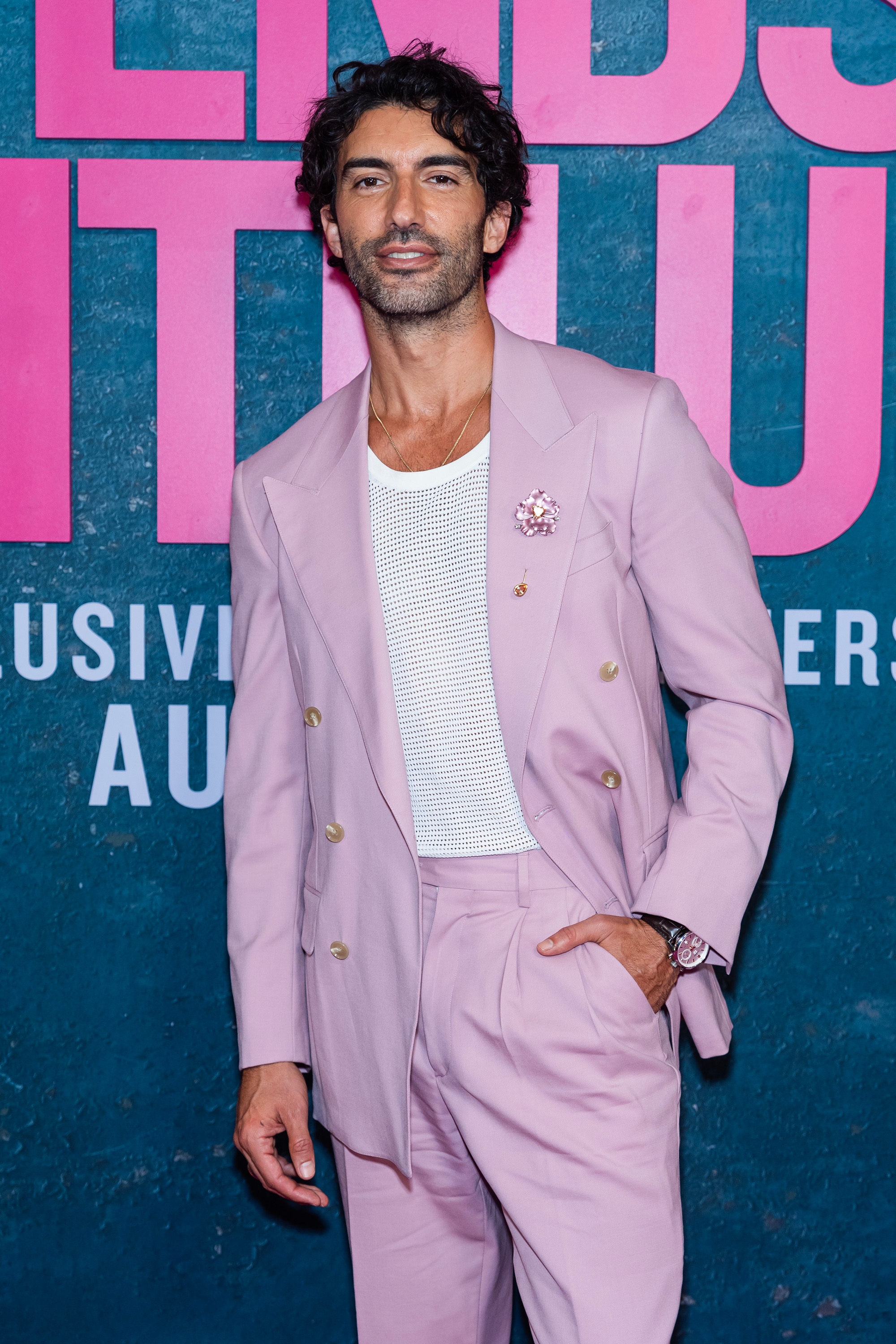 Person in a stylish suit with a relaxed mesh shirt at a celebrity event