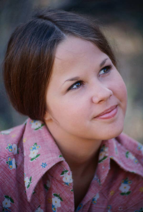 A person with a thoughtful expression looks upward. They are wearing a floral-patterned shirt