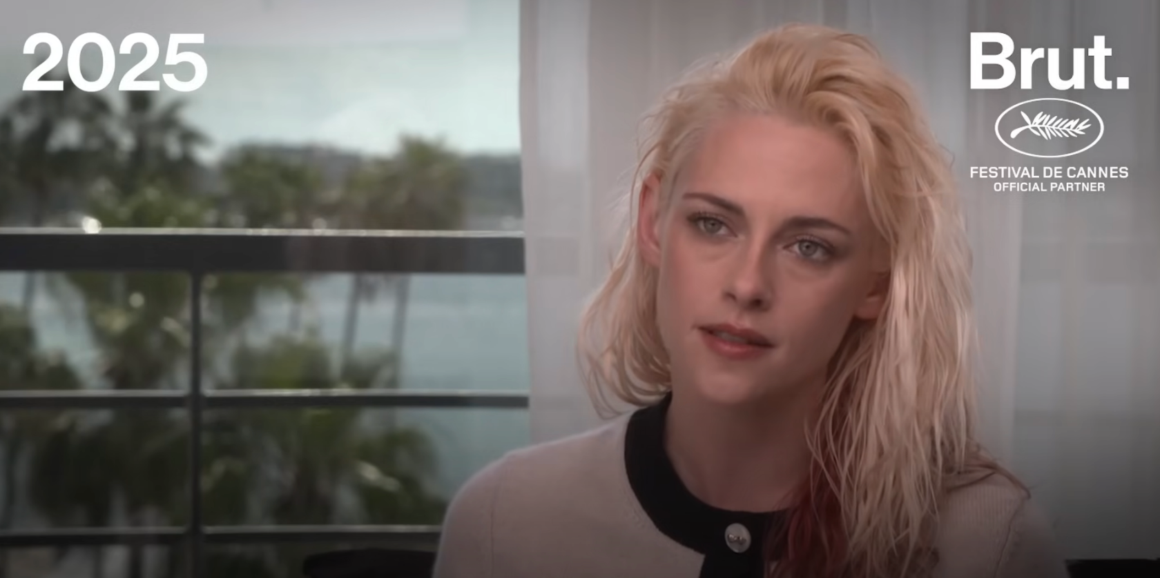 Person with wet hair styled, wearing a black and white top, sits in an interview setting. Background shows palm trees. Text reads: "2025" and "Brut."