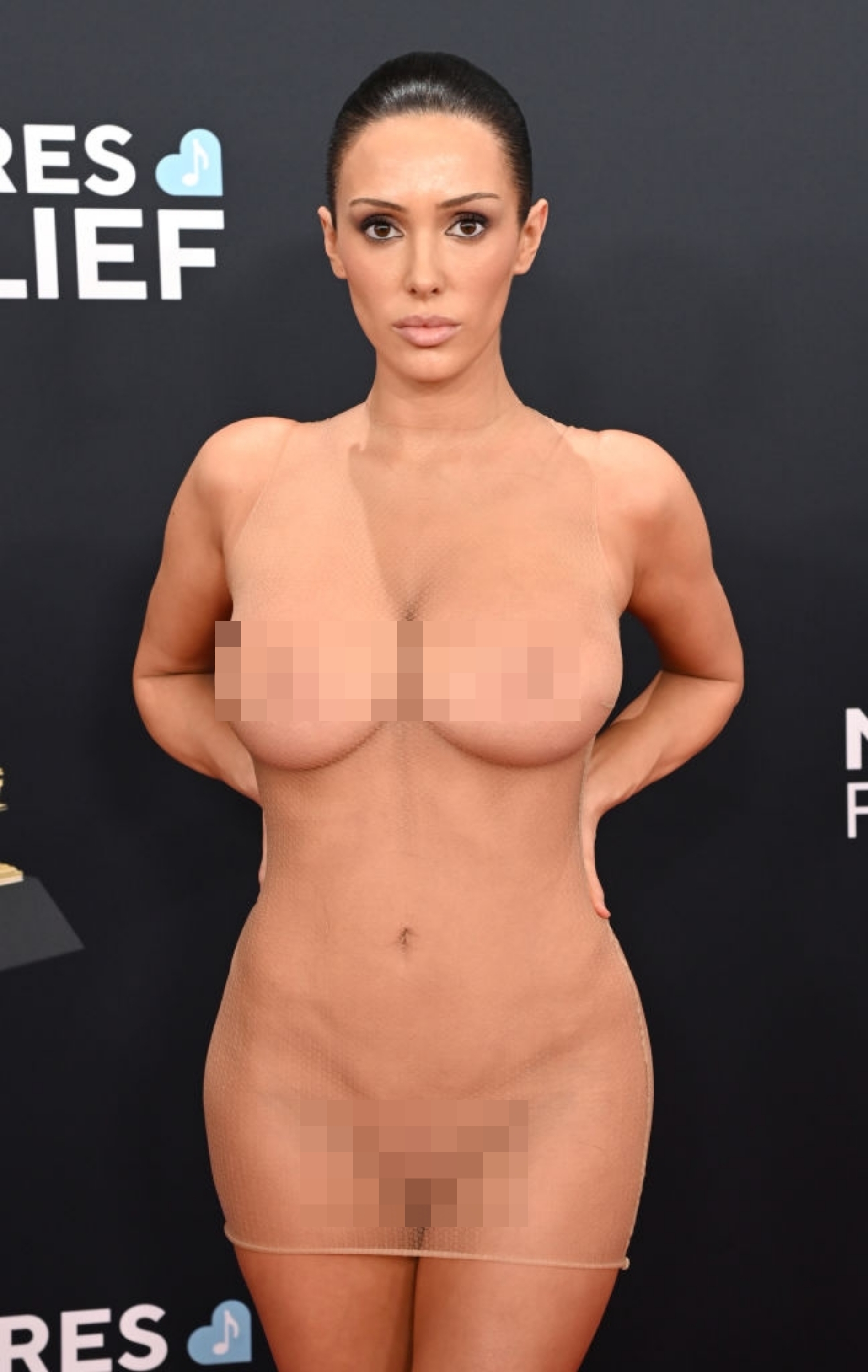 Biance on a red carpet wearing a form-fitting, sheer dress, styled with sleek hair