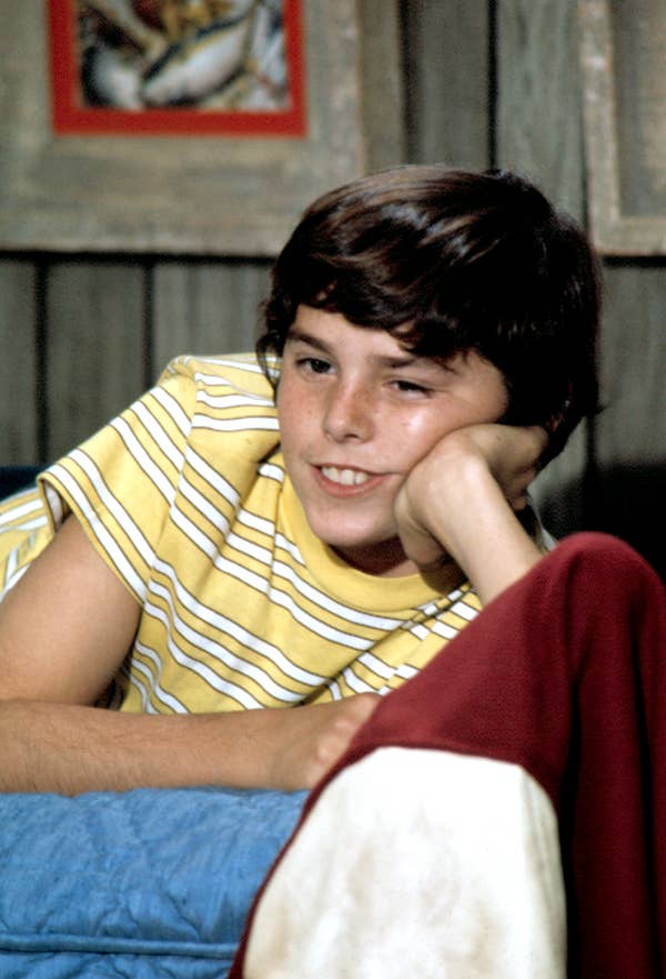 Person in a striped shirt is lounging casually, resting their head on their hand, with a relaxed expression