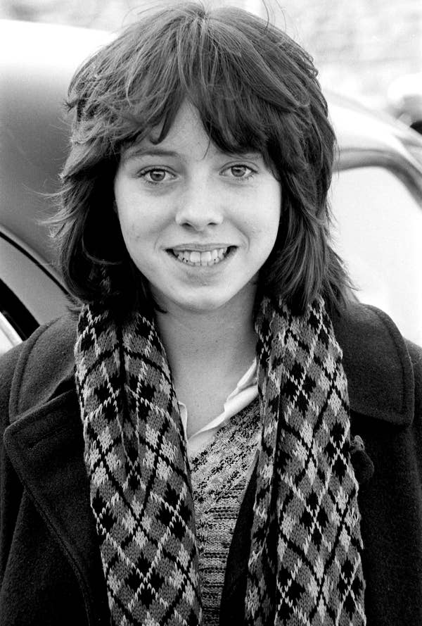 Person wearing a patterned scarf and coat, smiling outdoors