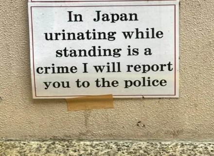 Sign in Japan warns against urinating while standing, stating it is a crime and will be reported to police