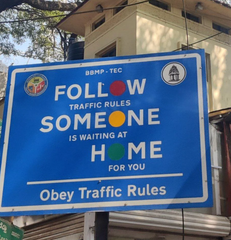 Street sign urging drivers to follow traffic rules, emphasizing that loved ones are waiting at home