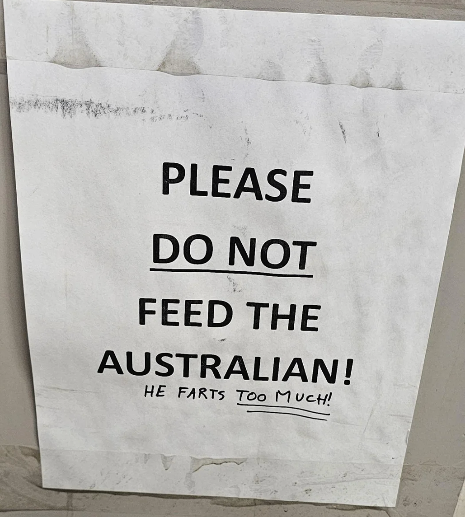 Sign reads: "Please do not feed the Australian! He farts too much!"