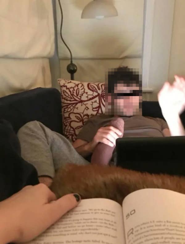 Person sitting on a couch with a tablet, while another person reads a book nearby. Cozy, relaxed setting