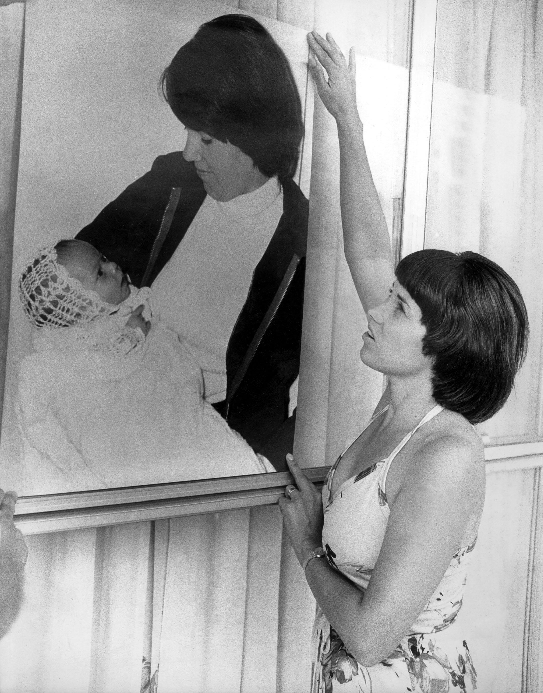 Woman adjusting a framed photo showing a man holding a baby
