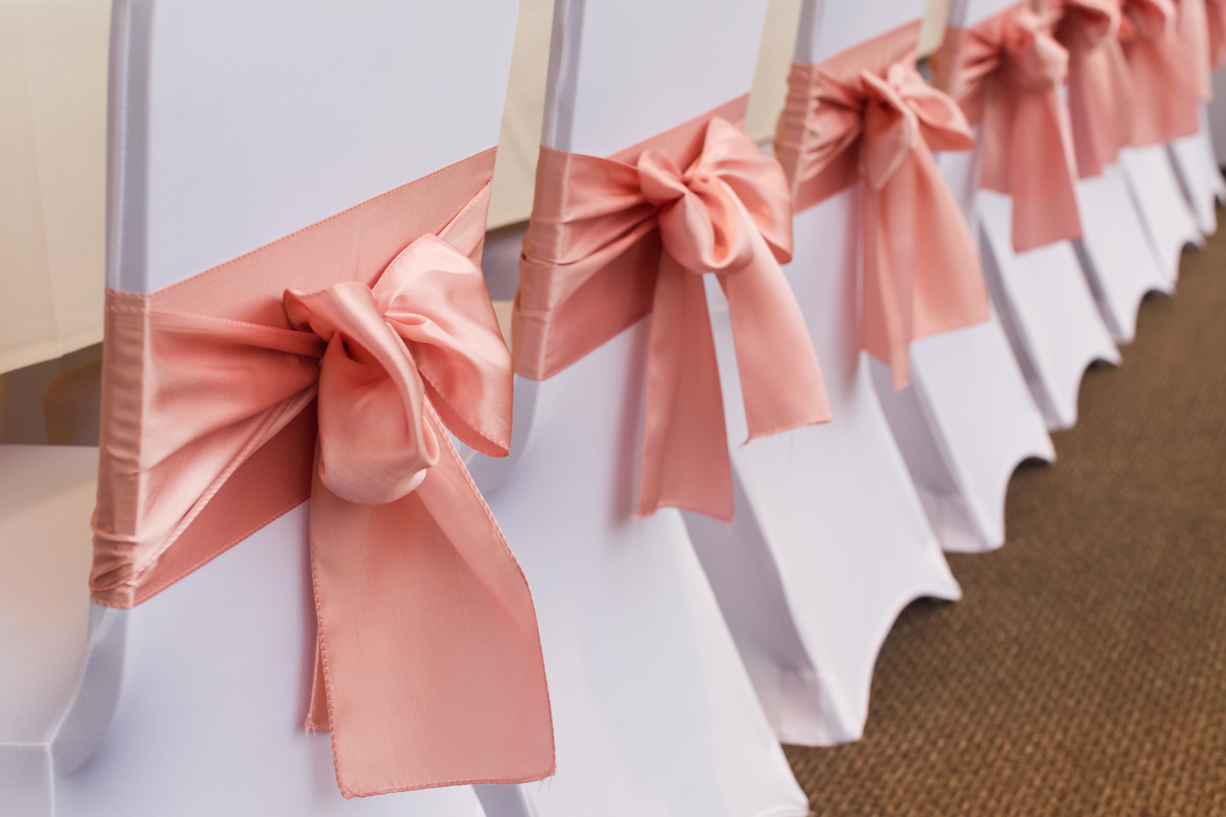 Wedding chairs elegantly decorated with satin bows, arranged in a row, creating a refined and festive atmosphere