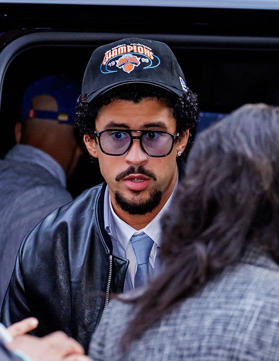 Man in leather jacket and cap with "champions" text exits a vehicle, facing a person in checkered attire