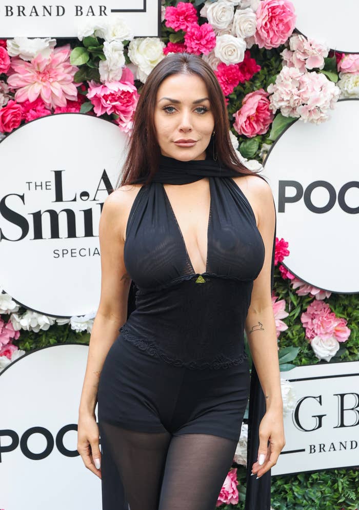 Courtney Stodden wearing a sleeveless, semi-sheer black jumpsuit with floral backdrop at an event