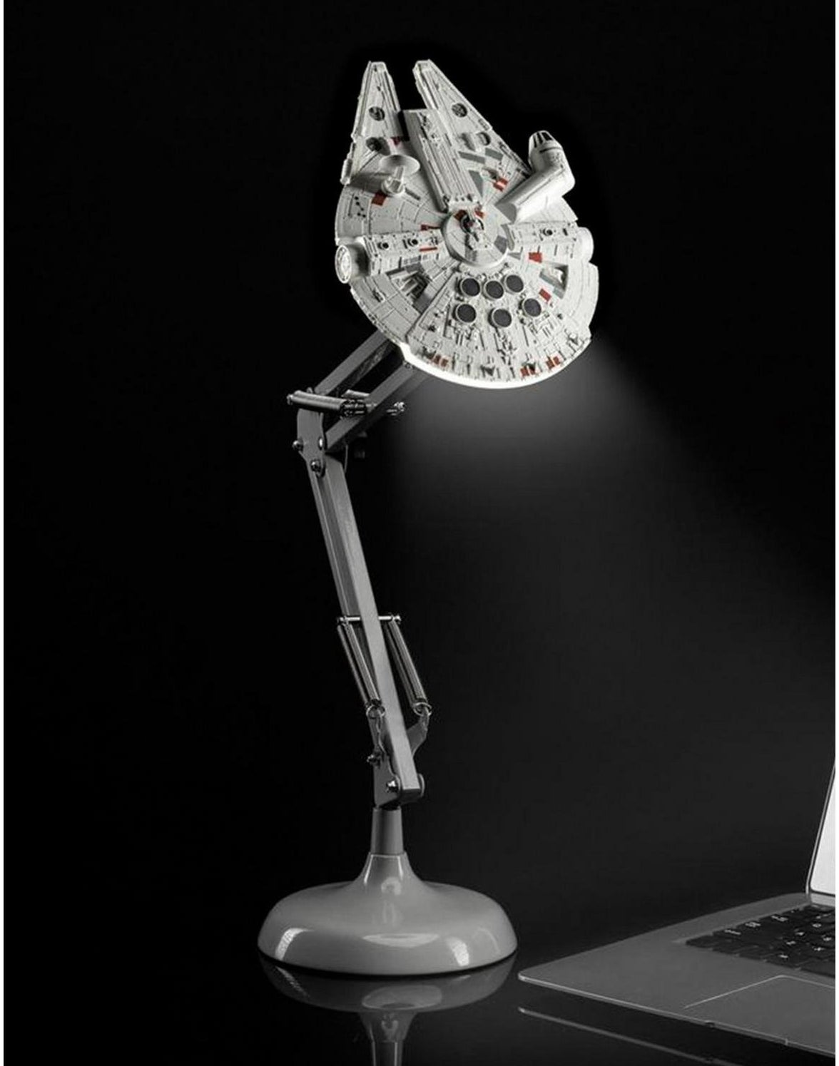 Star Wars-themed Millennium Falcon desk lamp shines light onto a laptop