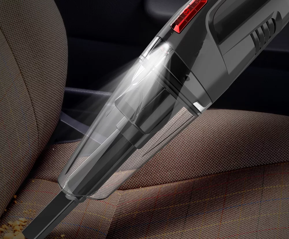Handheld vacuum cleaning crumbs from a car seat, highlighting its LED light feature for cleaning dark corners