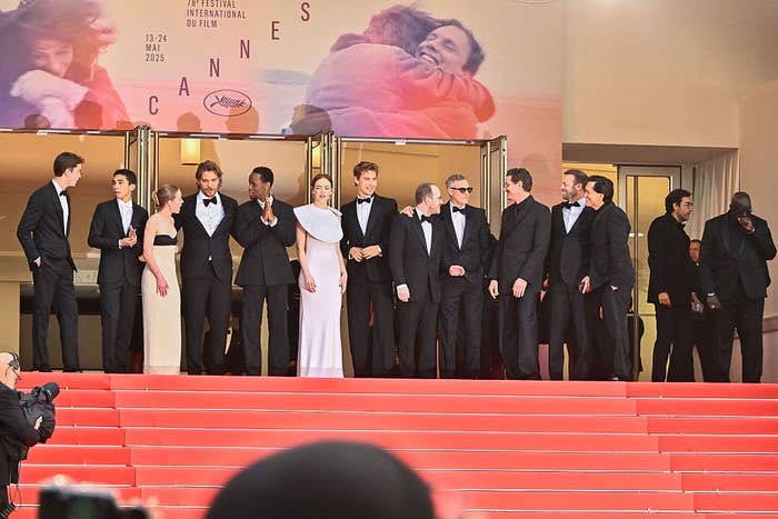Group of people in formal wear on a red carpet, posing at a film festival entrance