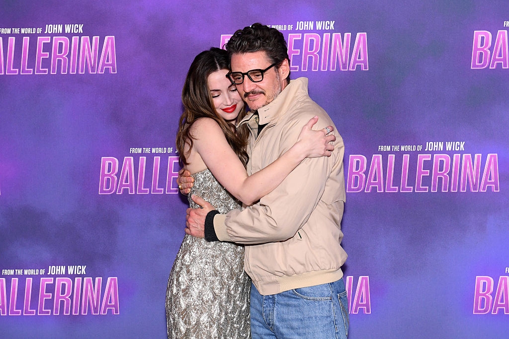 Two people embrace at the "Ballerina" event. One wears a sparkly dress, and the other a casual jacket and jeans