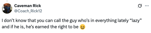 Tweet by Caveman Rick discussing someone being called "lazy," but suggests they've earned it through being prolific. Emoji of a laughing face included