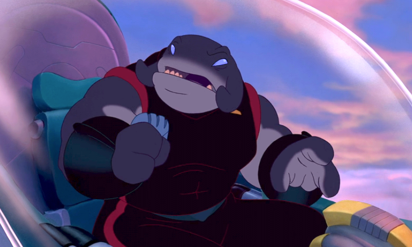 Animated character in a spaceship cockpit, wearing a dark armored suit, gesturing with a clenched fist, looking determined. Sky visible through the window