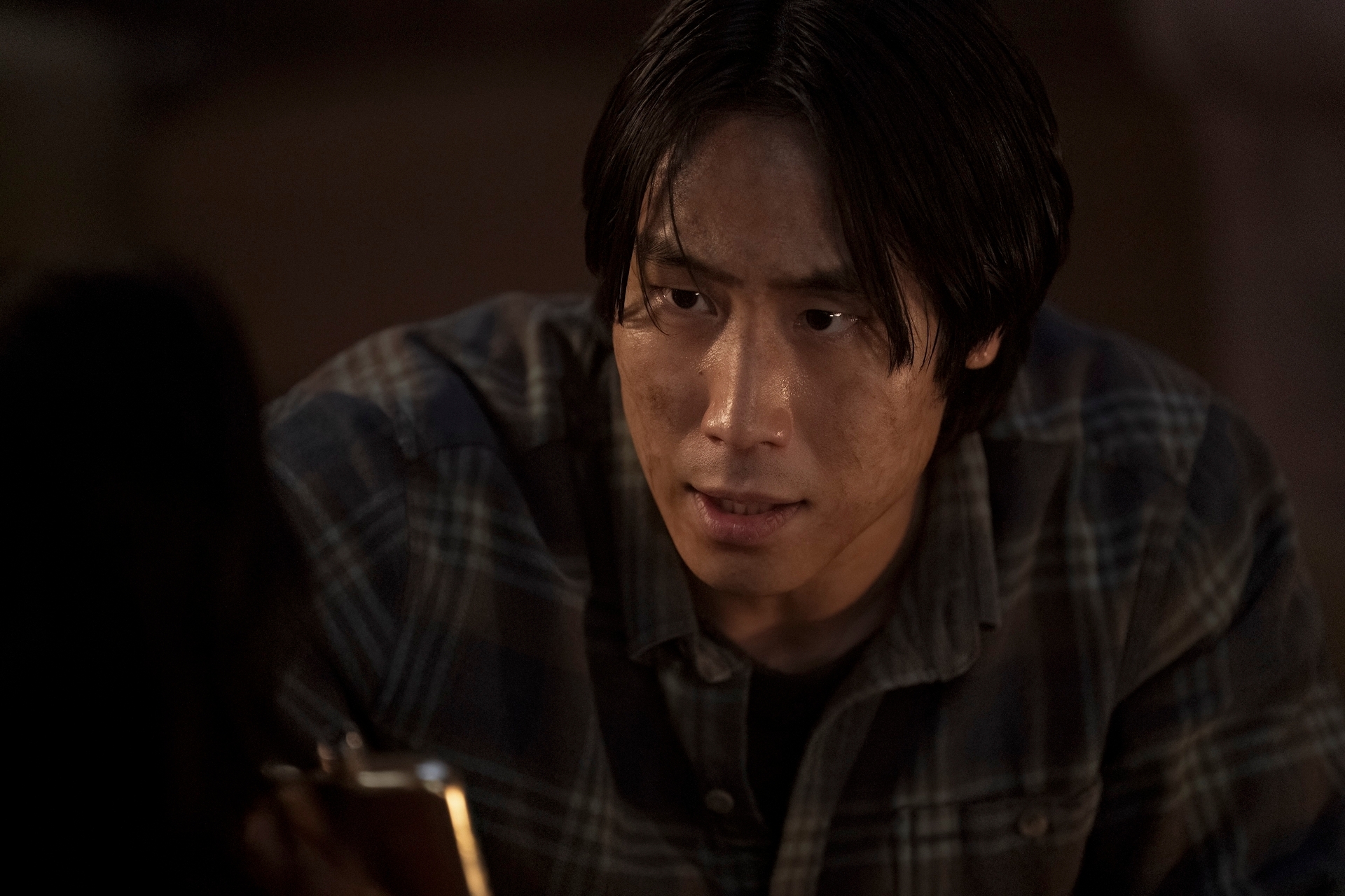 Persona con expresión pensativa, mirando algo fuera de cámara, lleva camisa a cuadros