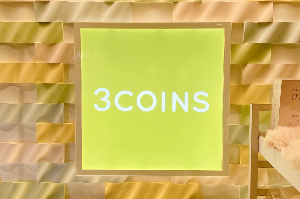 「3COINS」のロゴがあるショップの看板。背景は立体的なパネルで装飾。