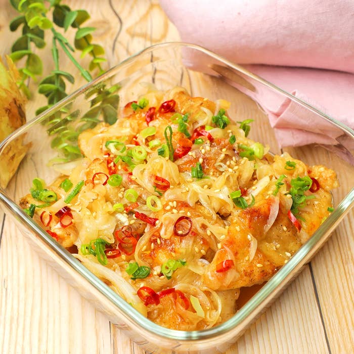 鶏の唐揚げにネギと唐辛子をトッピングした盛り付け。ガラスの皿に盛られ、食欲をそそる見た目。