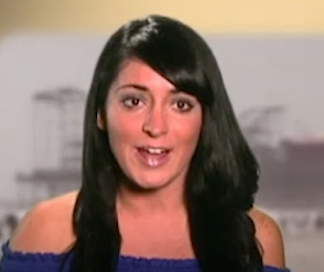 A person with long dark hair and an off-shoulder top speaks directly to the camera, likely in a TV show or interview setting