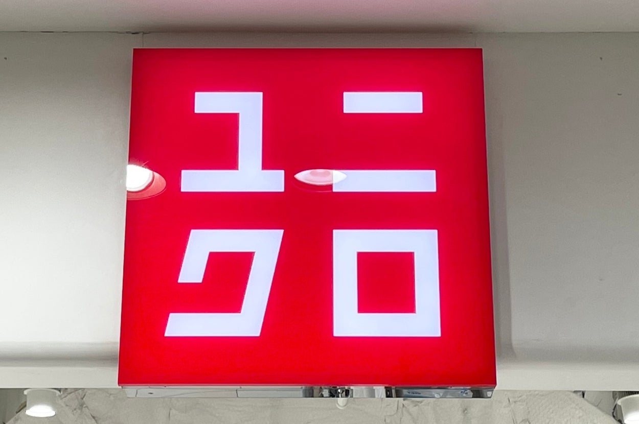 A red Uniqlo store sign with stylized Japanese katakana characters above an entrance