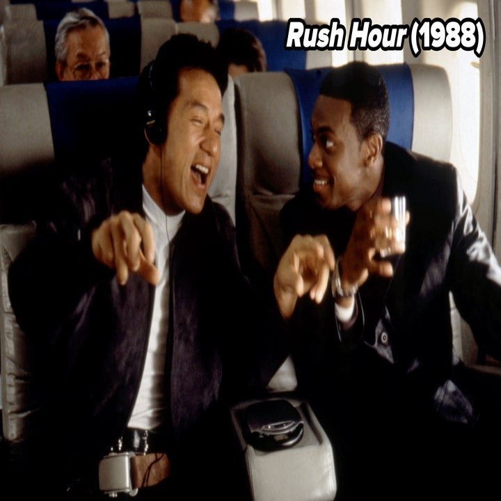Two people laughing and enjoying a conversation on an airplane. One is wearing headphones, and the other is holding a drink, both seated comfortably