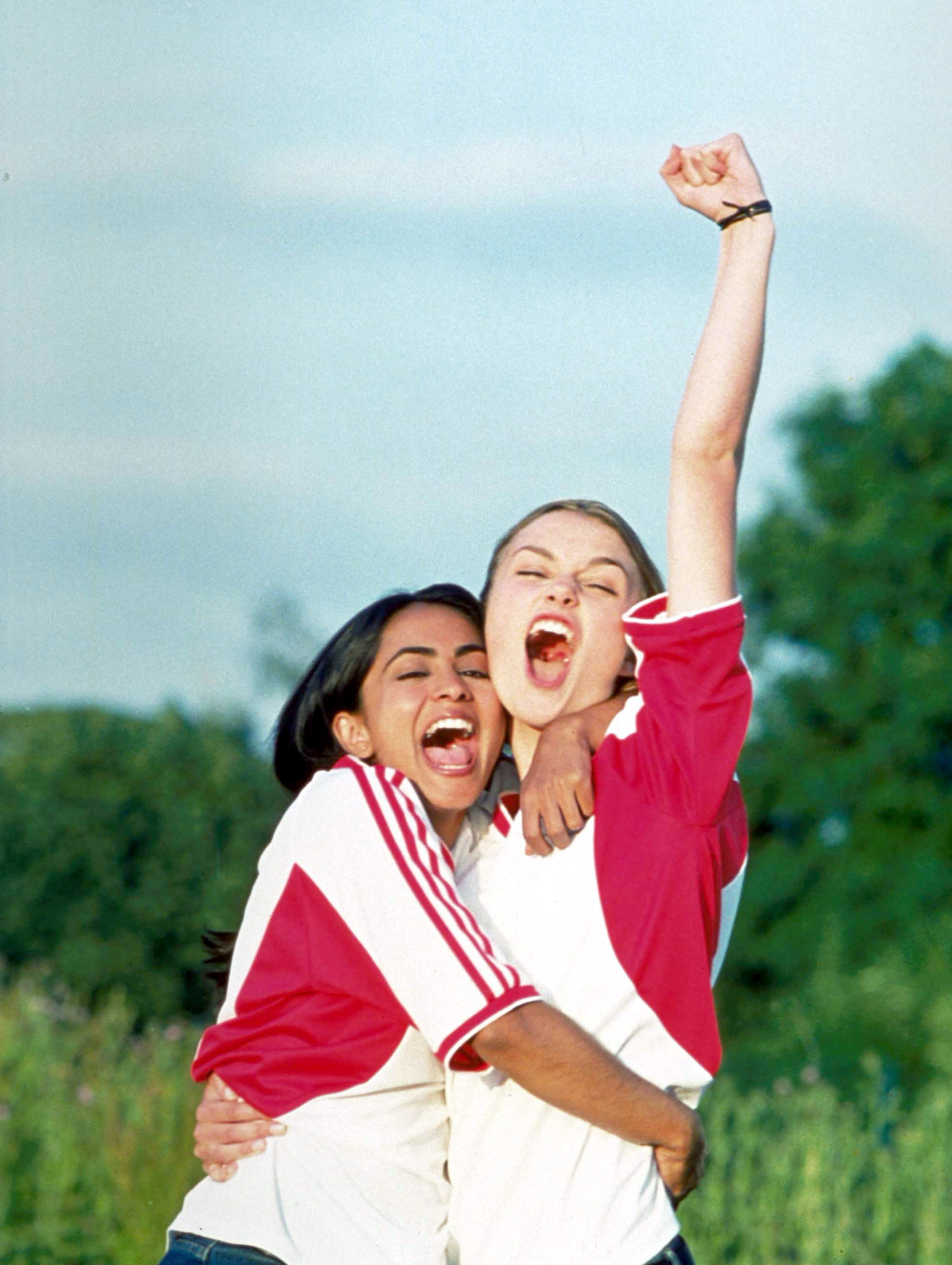 Parminder K. Nagra and Keira Knightley outdoors looking joyful in a movie scene