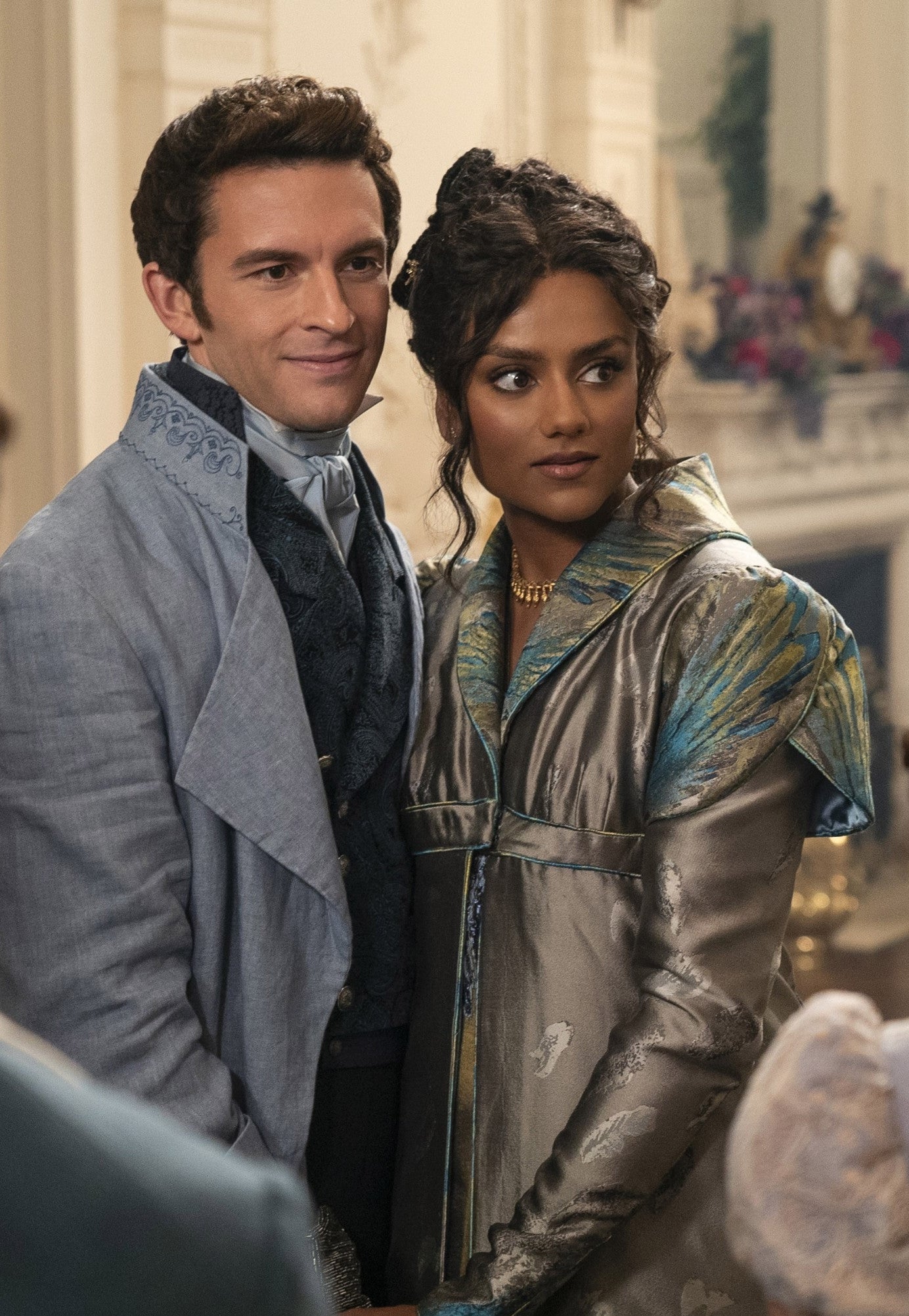 Jonathan Bailey and Simone Ashley standing next to each other in a TV scene