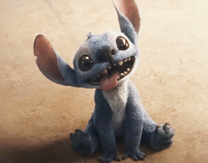Stitch sits on the ground with a playful expression and tongue out