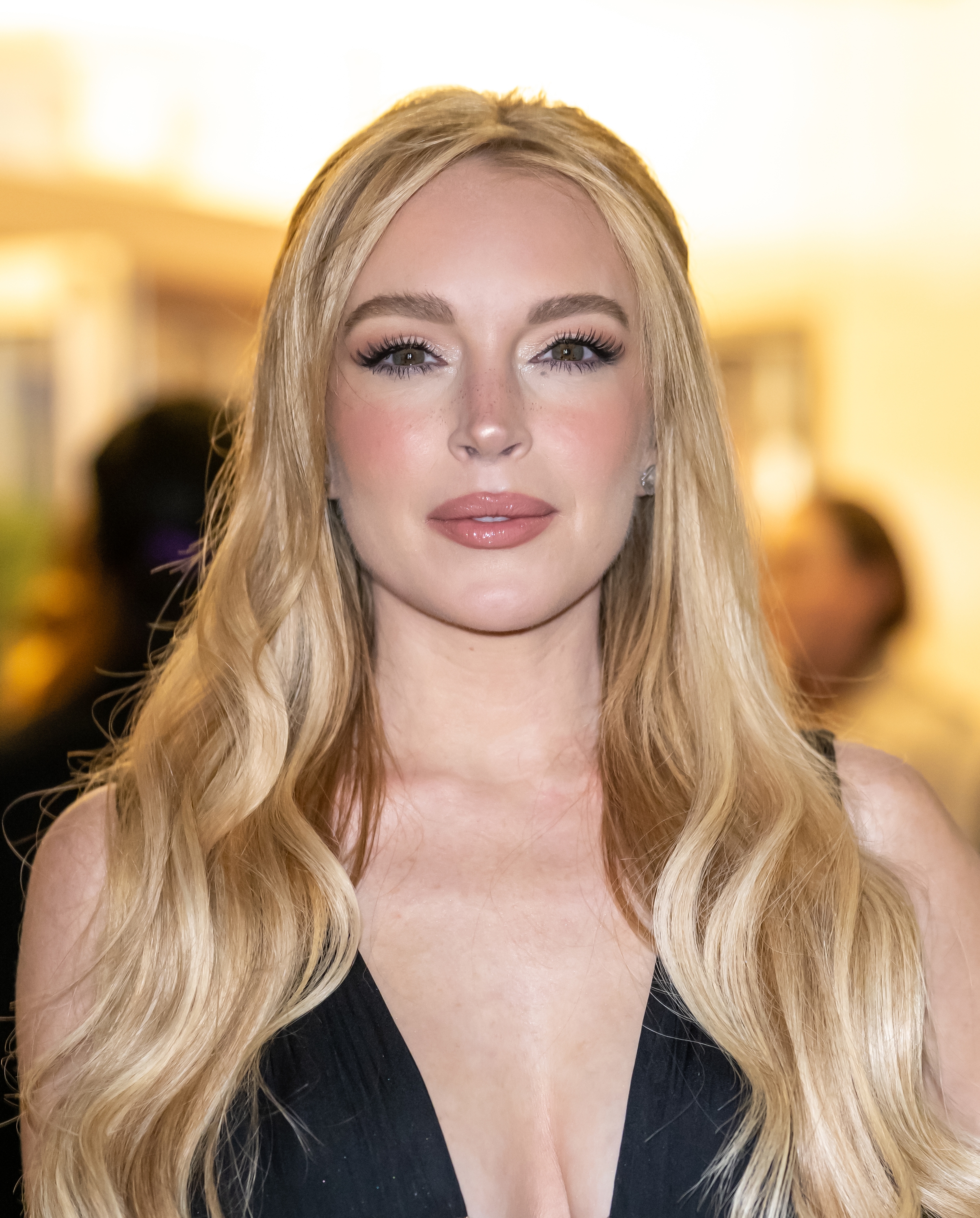 Person with long hair in elegant evening attire poses on a red carpet at a celebrity event