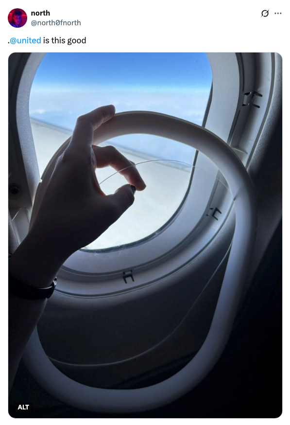 A hand holding an inflatable neck pillow in front of an airplane window, suggesting a comfortable flight experience