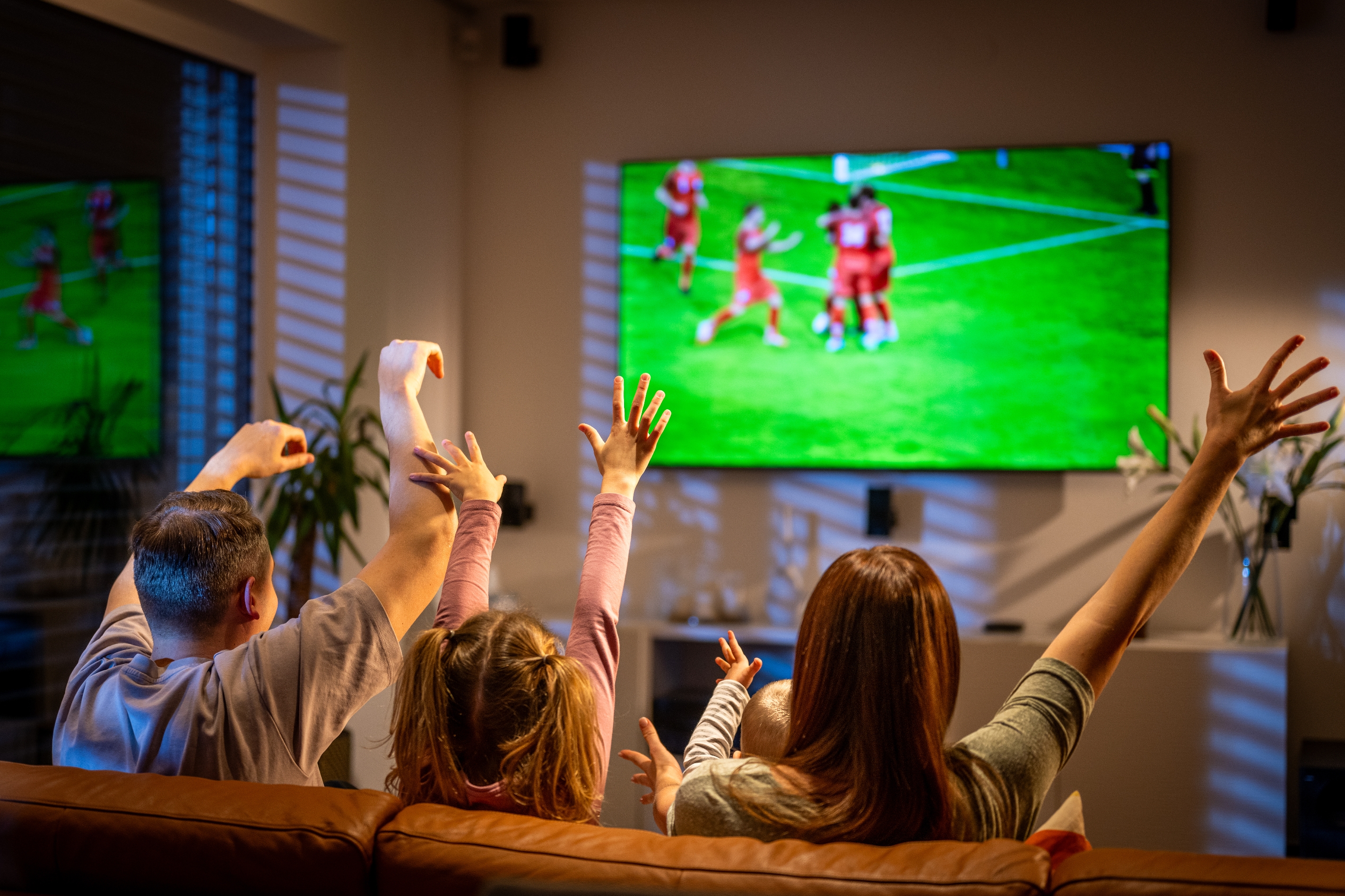 Family cheering while watching a soccer game on TV in a cozy living room