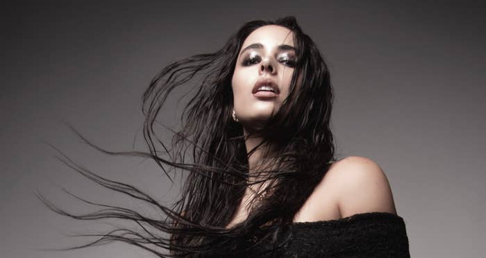 Persona posando frente a la cámara con el cabello suelto y ondulado. Lleva un vestido con hombros descubiertos