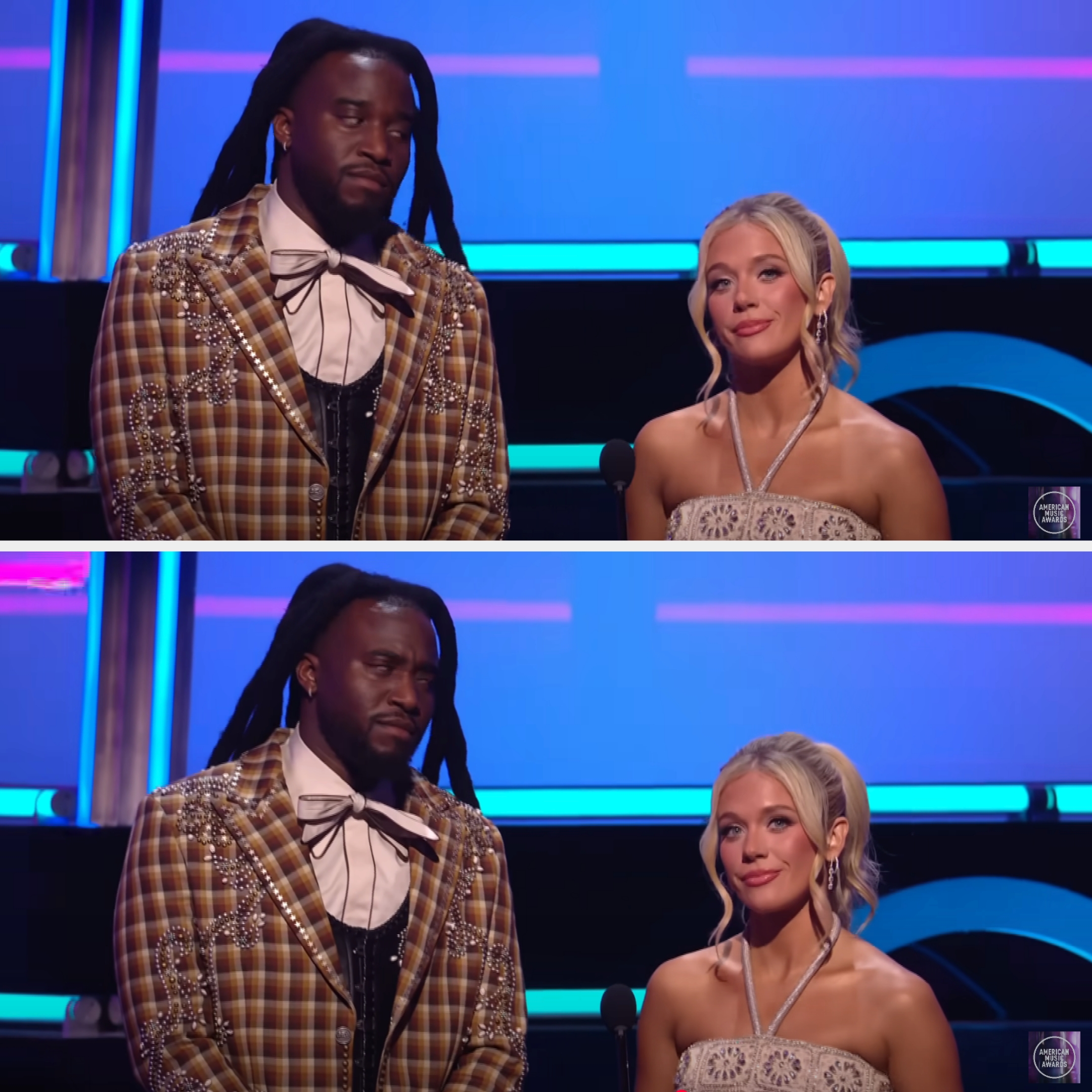 Two people on stage: one in a plaid suit with a tie, the other in a halter neck dress. They appear to be presenting at an event