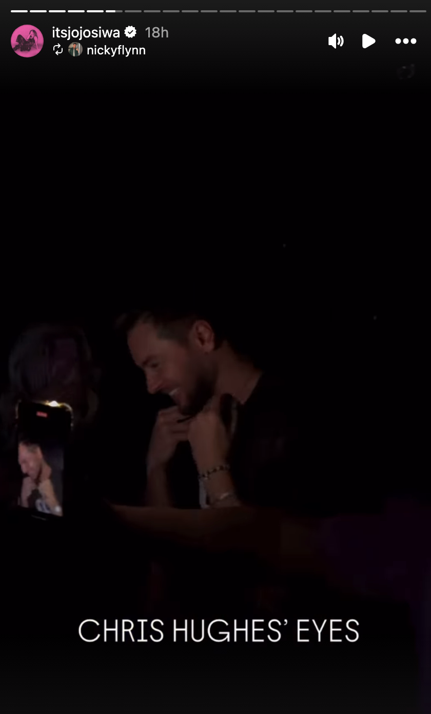 Man smiling, captured in dark setting, surrounded by cameras. Overlay text: "CHRIS HUGHES’ EYES"