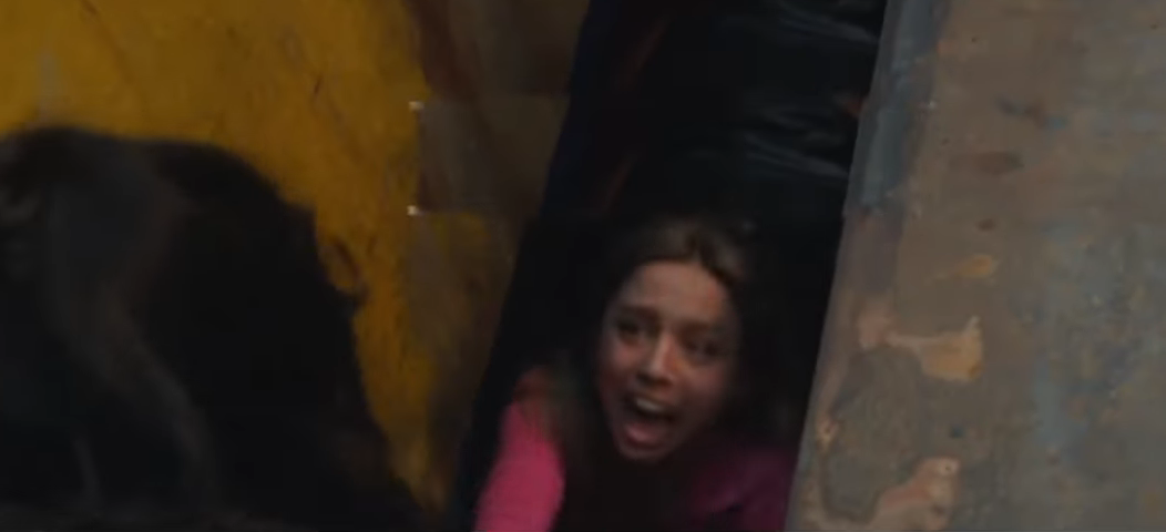 Person reaching out through a narrow space, appearing distressed. Scene suggests urgency or a challenging situation