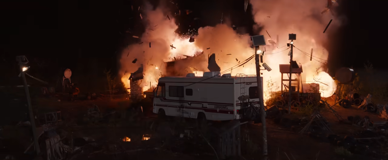 Explosion at night with debris flying and an RV nearby, suggesting a dramatic scene or event